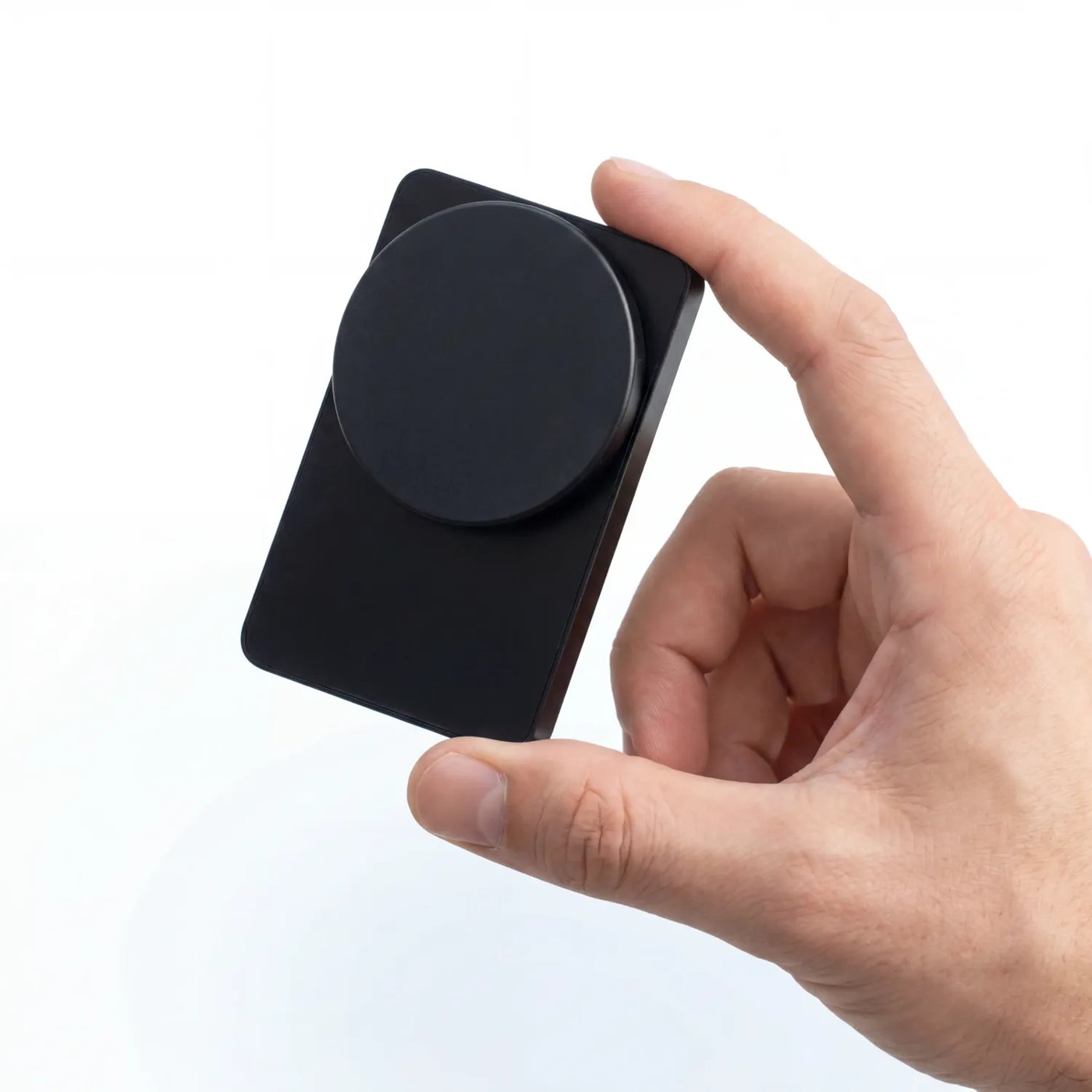 Hand holding the ERA from the back with the round magnetic charging pad clipped onto it.